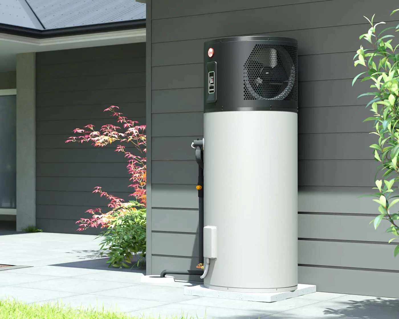 Heat pump water heater installed outside modern home with gray siding, surrounded by Japanese maple and green plants.