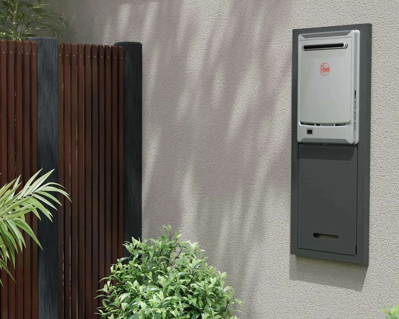 Rheem water heater mounted on exterior wall with wooden fence and green plants nearby.