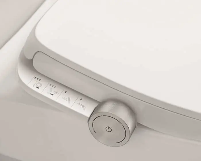 Close-up of a white electronic toilet seat with control panel and power button on the side.