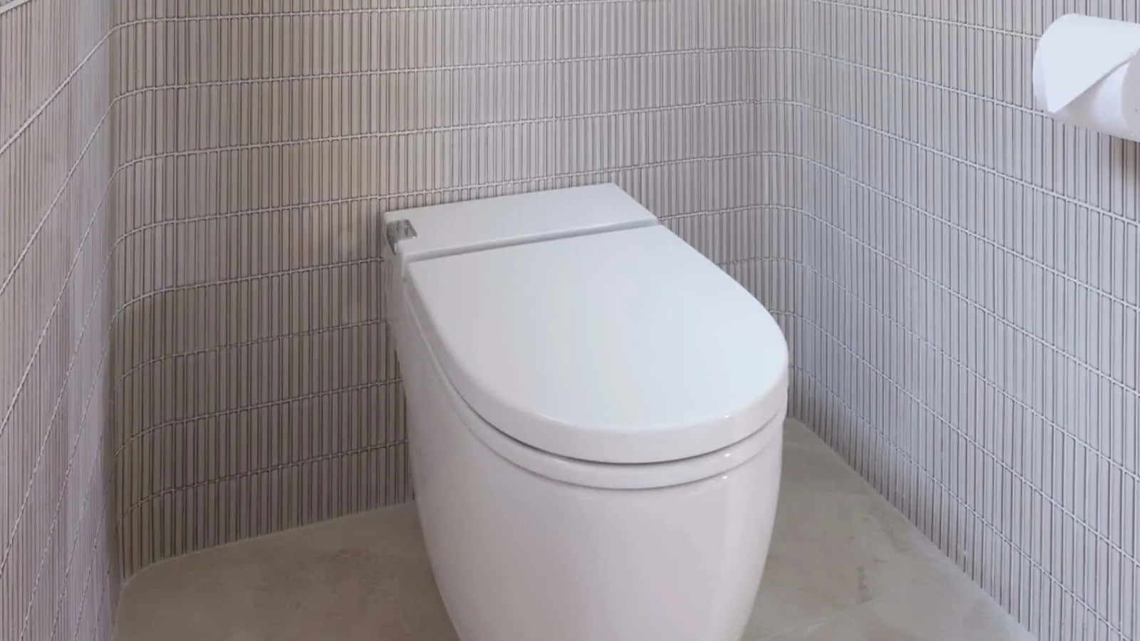 Modern white toilet in a bathroom with vertical striped light gray wall tiles.