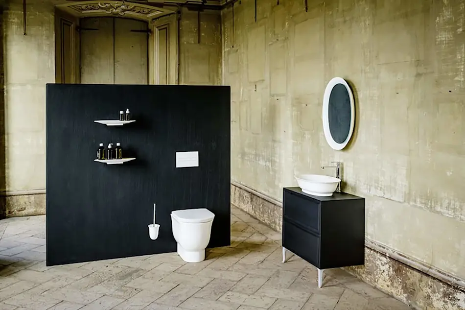 Modern bathroom with black partition wall, white toilet, black vanity with vessel sink, and round mirror in a vintage room.