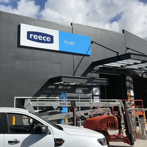 Reece HVAC storefront with blue and white signage on a gray building, construction equipment visible below.
