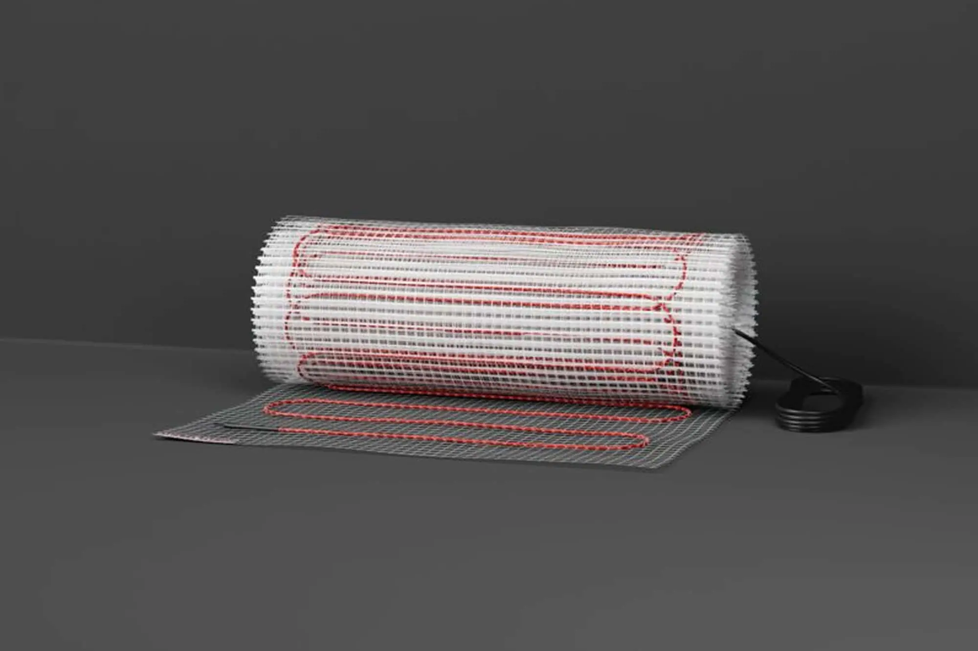 Electric floor heating mat with red wiring partially rolled out on gray background with power connector visible.