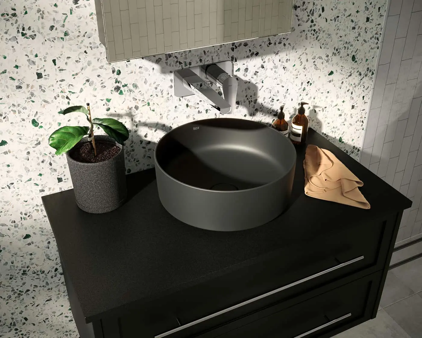 Modern bathroom vanity with black countertop, round metal sink, potted plant, and terrazzo wall background.