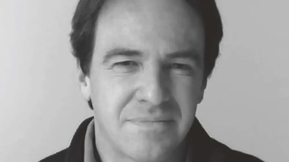 Close-up black and white portrait of a person with short dark hair against a plain background.
