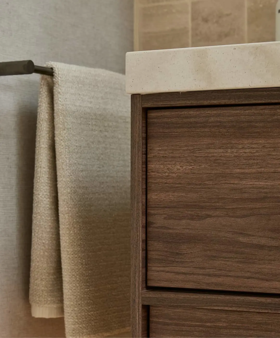 Modern bathroom with wooden vanity, white countertop and towel on rack.