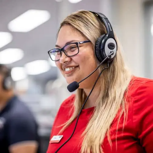 Customer service representative wearing headset and glasses smiling in an office environment