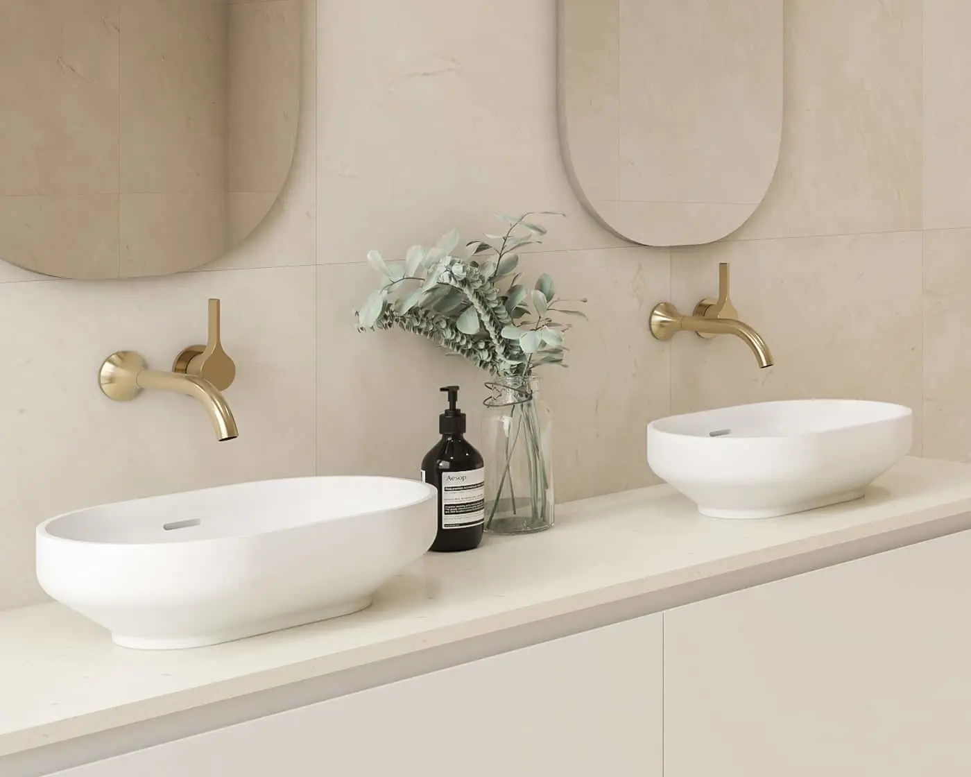 Modern bathroom with dual white vessel sinks, brass wall-mounted faucets, and eucalyptus arrangement between basins.