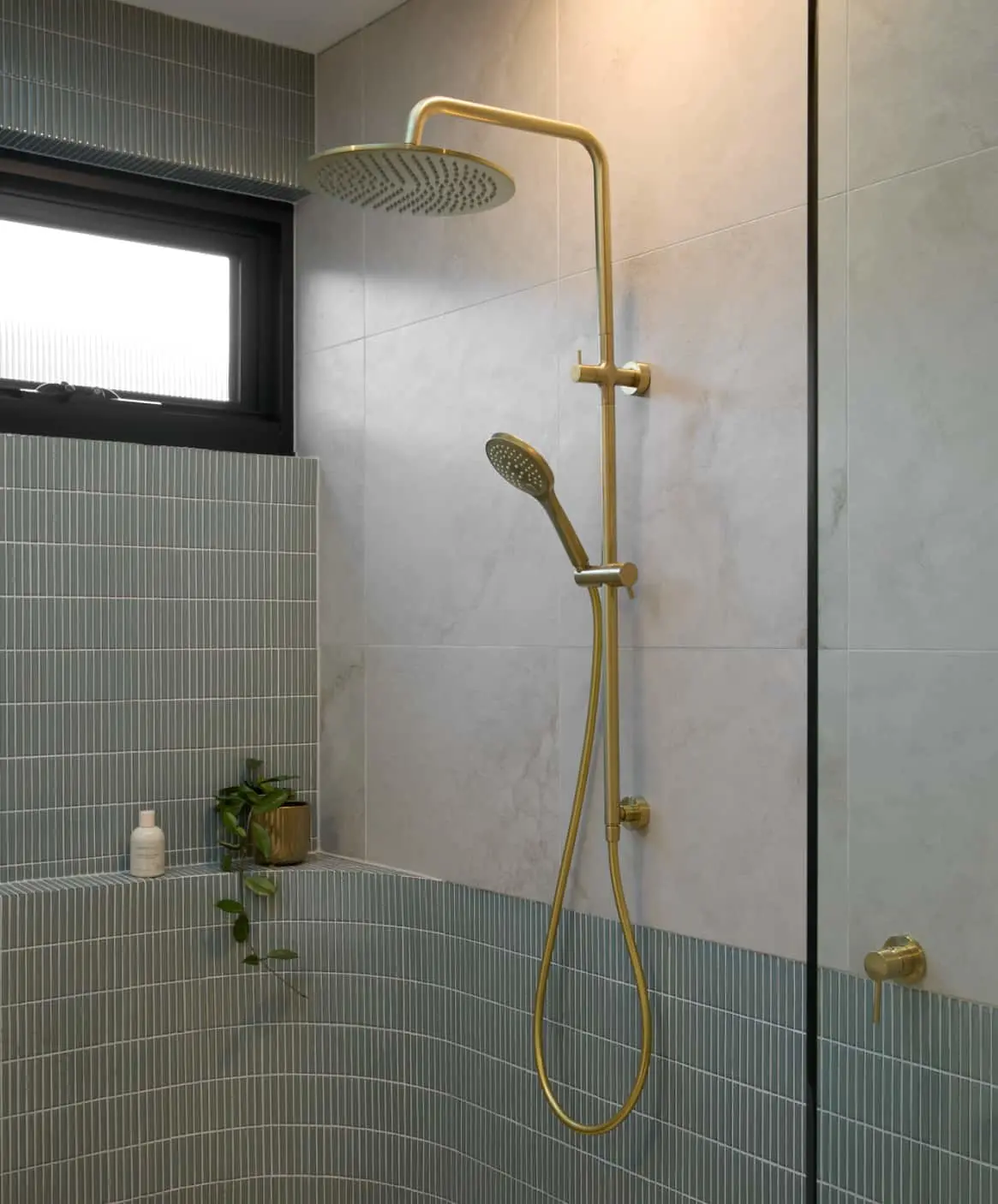 Modern bathroom with gold fixtures featuring a walk-in shower with rainfall head.