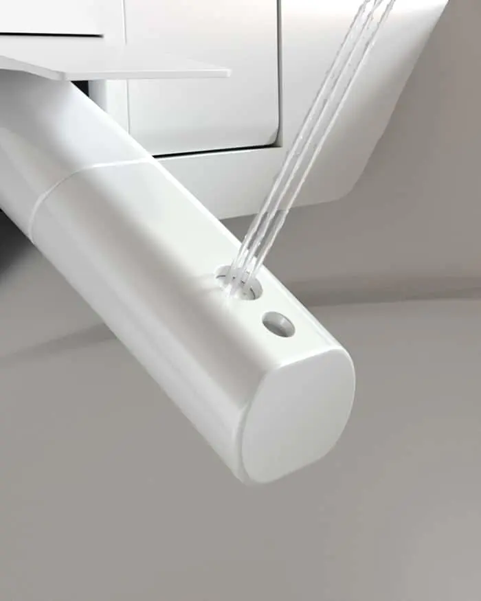 Close-up of a white toilet with a bidet attachment or nozzle extending from under the seat.