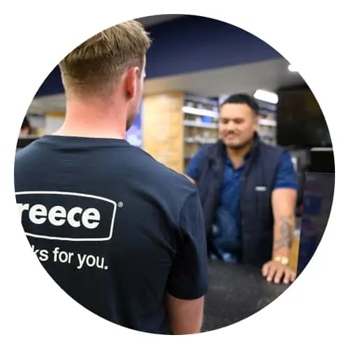 Two people conversing at a retail counter, one wearing a black shirt with partial logo visible.