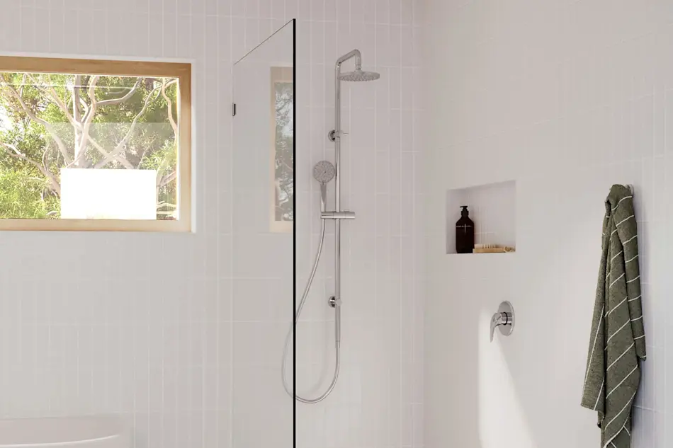 Modern white bathroom with glass shower, window overlooking trees, built-in shelf, and green striped towel hanging on wall.