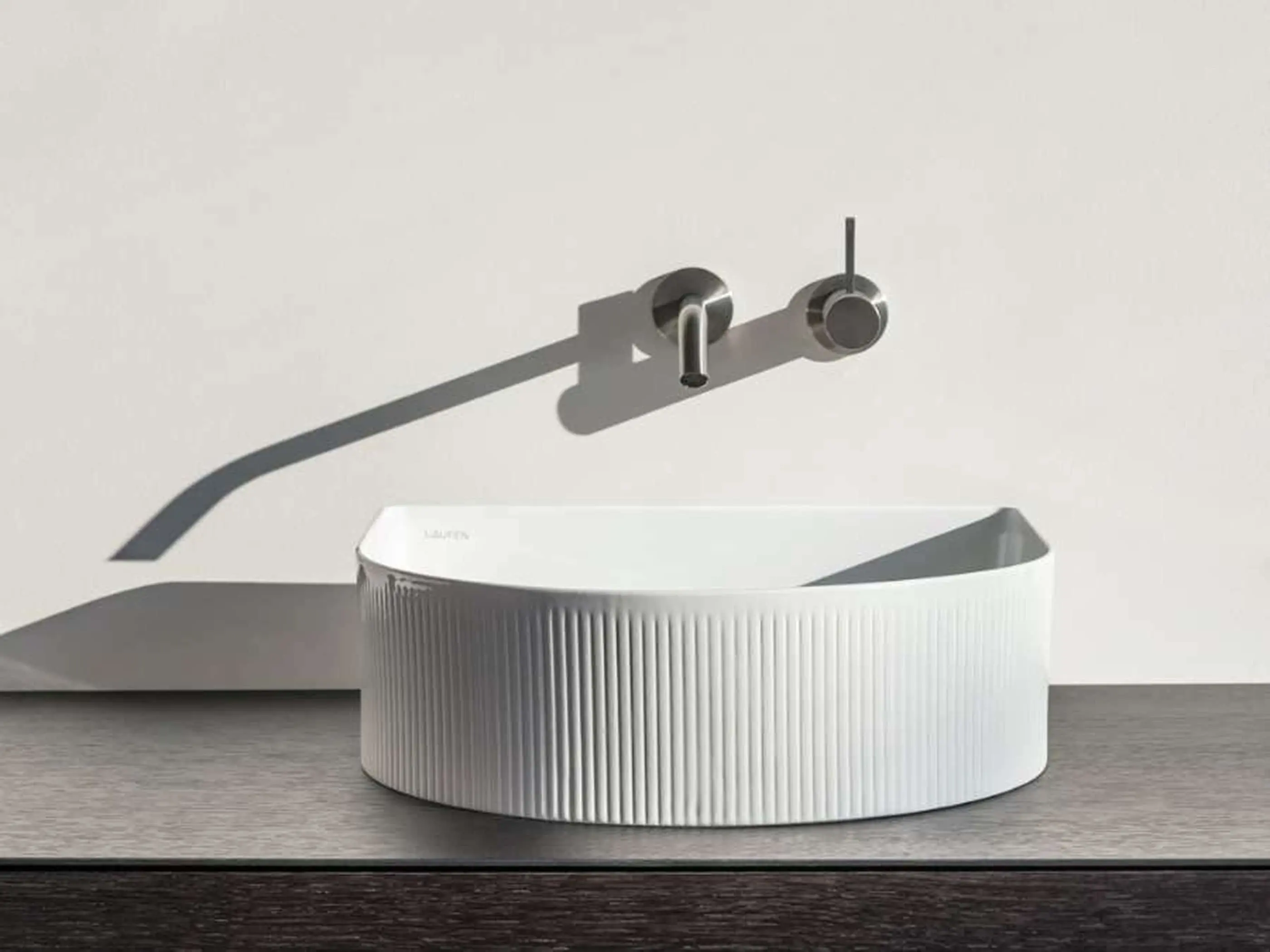 Modern white oval bathroom sink with vertical ridged texture and wall-mounted stainless steel faucet on gray surface.