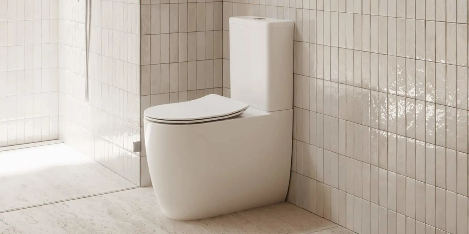 Modern white toilet with closed lid in a minimalist bathroom with beige tiled walls and light floor.