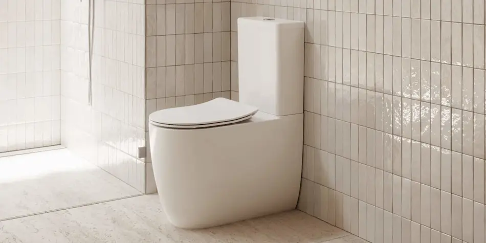 Modern white toilet with closed lid in a minimalist bathroom with beige tiled walls and light floor.