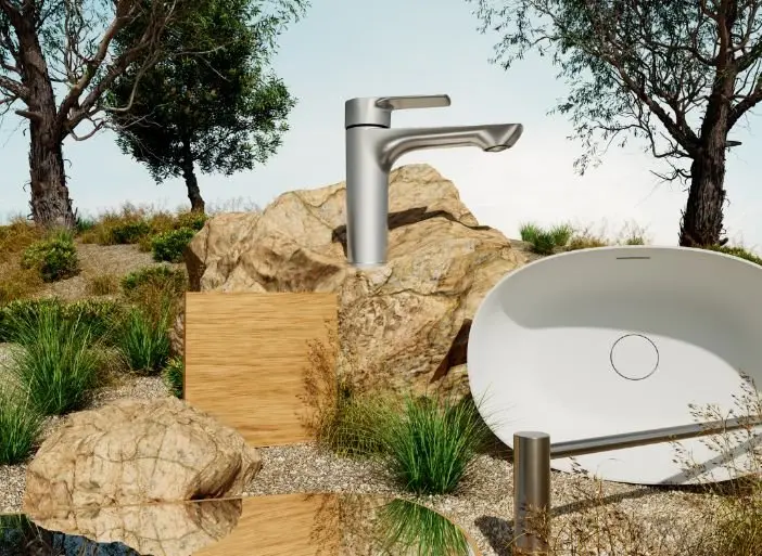 Modern outdoor bathroom sink with silver faucet set among natural rocks and greenery in a garden landscape.