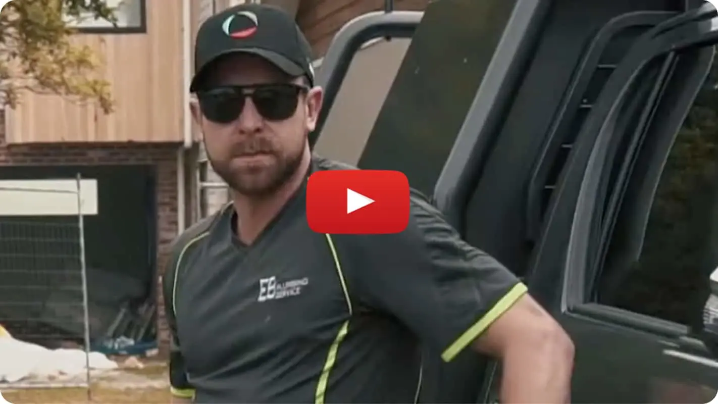 Person in dark polo shirt and cap standing next to vehicle with YouTube play button overlay on the image.