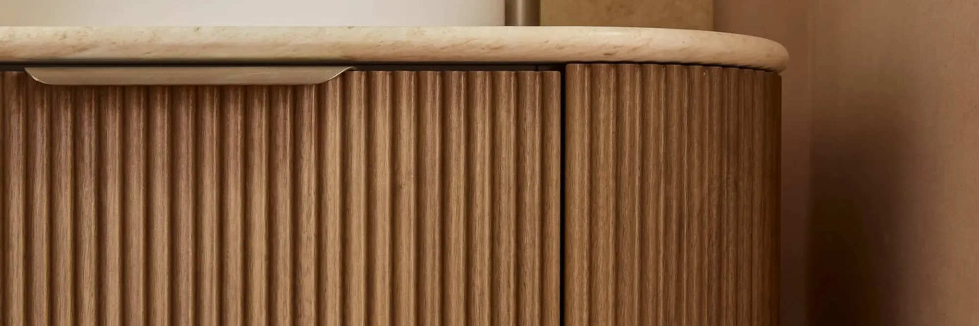 Modern wooden cabinet with vertical ribbed texture and light stone or marble countertop.