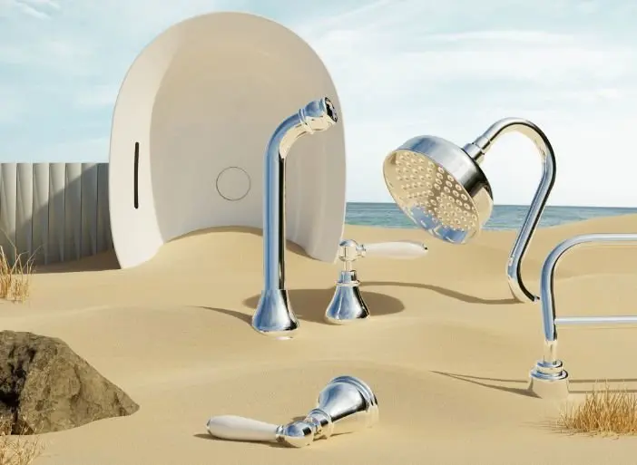 Chrome shower fixtures arranged on a sandy beach with an egg-shaped white structure and ocean in the background.