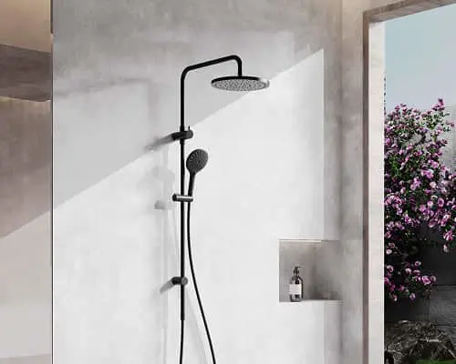 Black shower system with rainfall head and handheld sprayer mounted on white bathroom wall with window view of flowers.