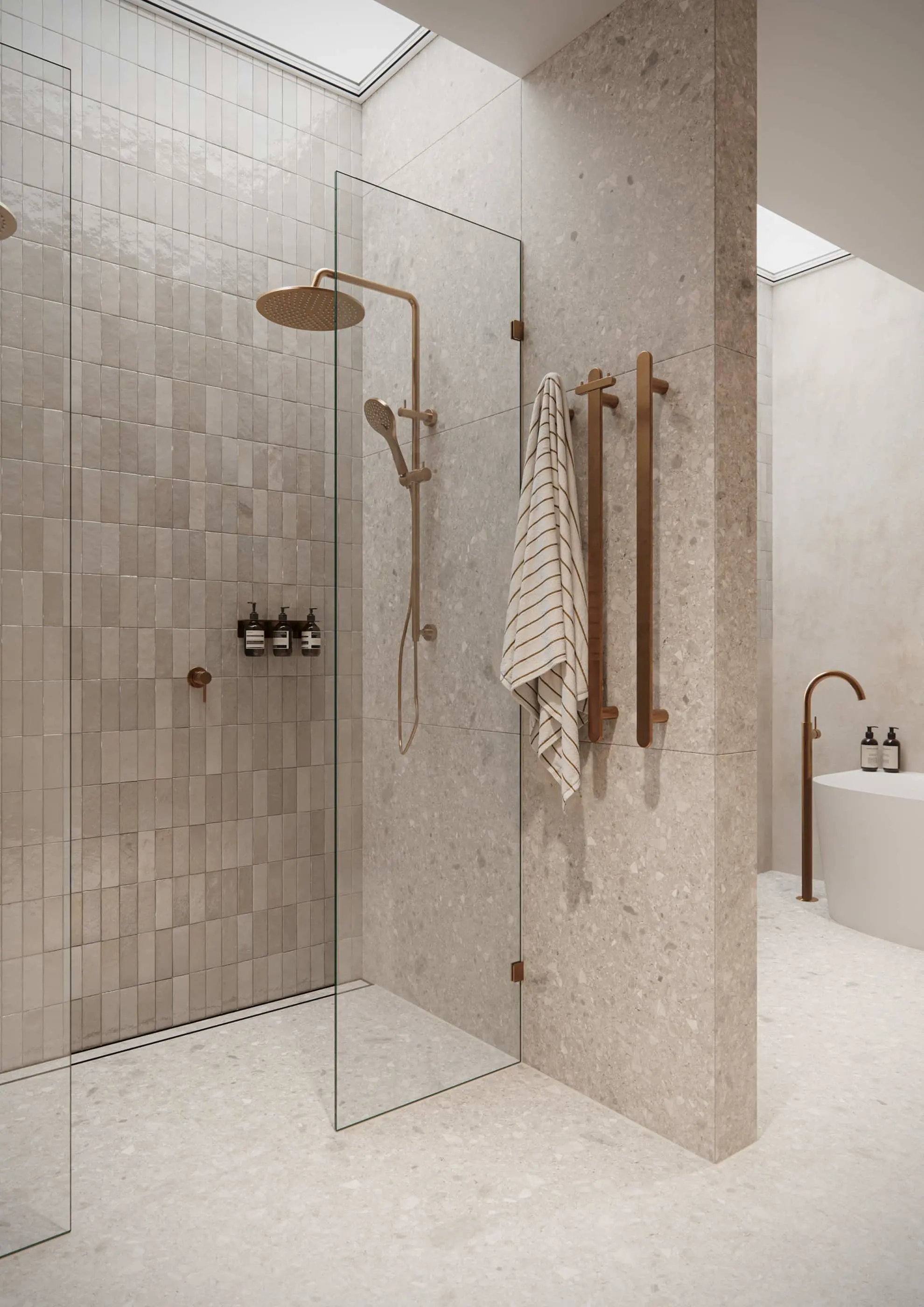 Modern bathroom with glass shower, beige tile walls, brass fixtures, striped towel on wooden hooks, and skylight above.