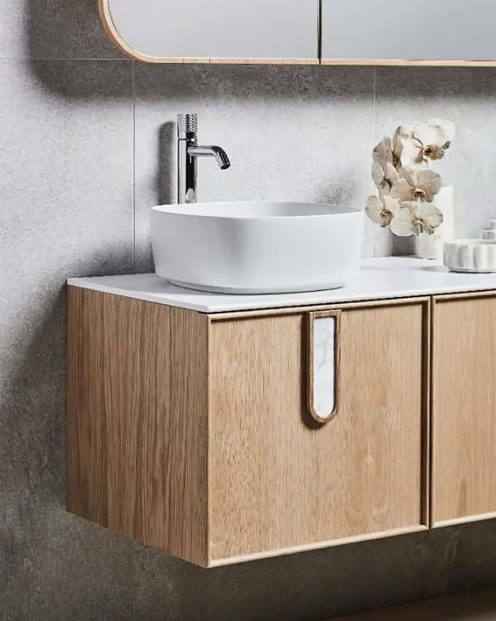 Modern bathroom vanity with white vessel sink on wooden cabinet, chrome faucet, and white orchid decoration.