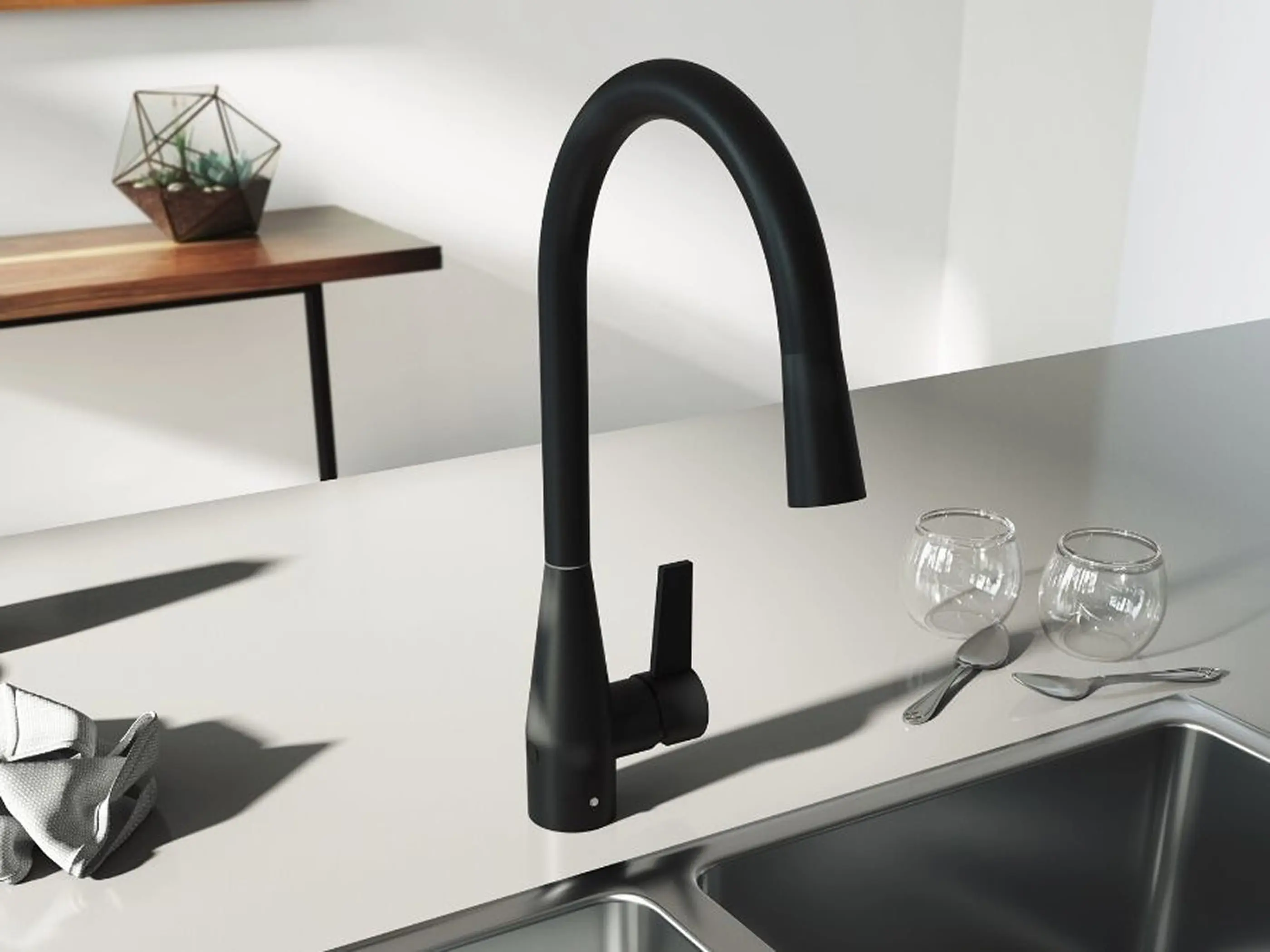 Modern black kitchen faucet with pull-down sprayer on white countertop, next to sink with glassware and utensils nearby.