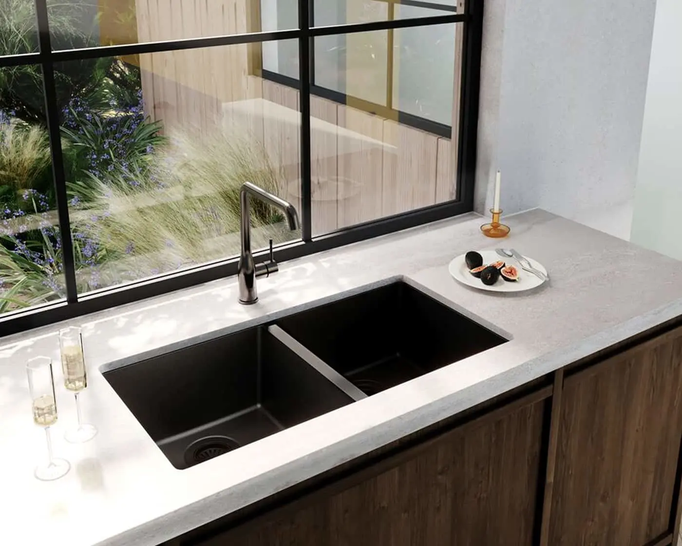 Modern kitchen with black double sink, gray countertop, and large windows overlooking ornamental grasses and flowers.