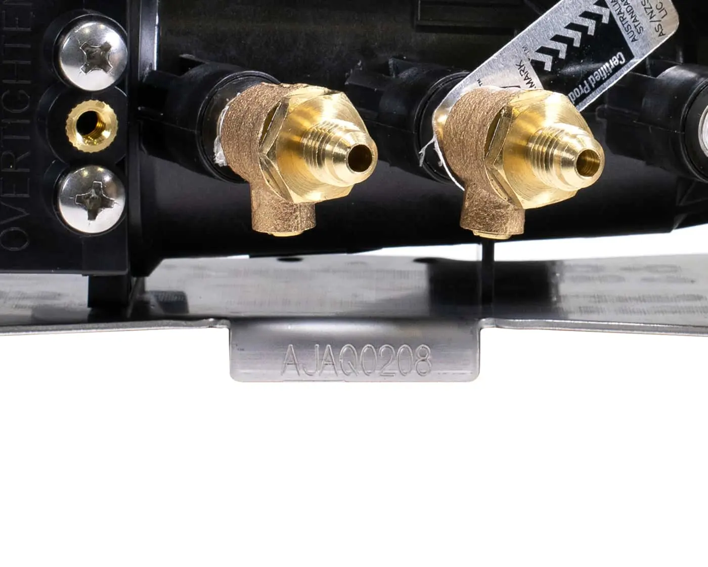 Close-up of brass plumbing fittings on a black manifold with serial number visible on metal base plate.