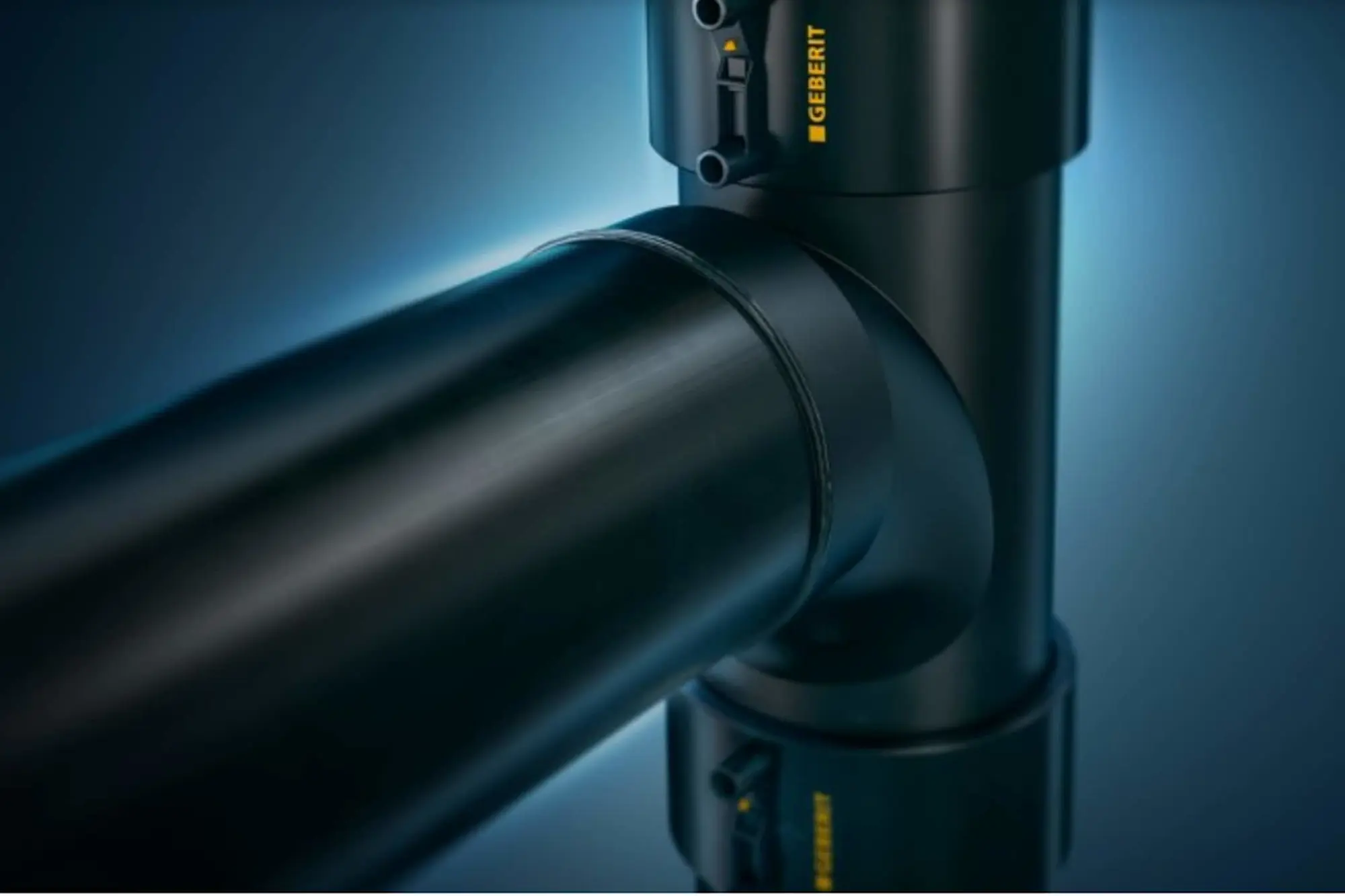 Close-up of black industrial pipe joints with Geberit branding against blue background.