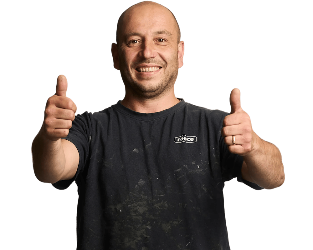 Person in Reece t-shirt with logo giving thumbs up with both hands, smiling against white background.