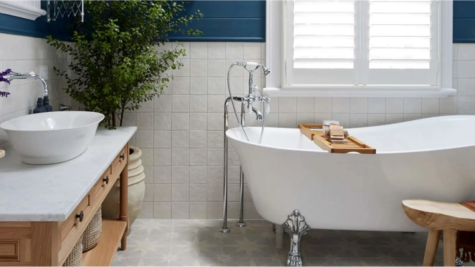 Modern bathroom with white clawfoot tub, wooden vanity, vessel sink, and green plant against blue and white walls.