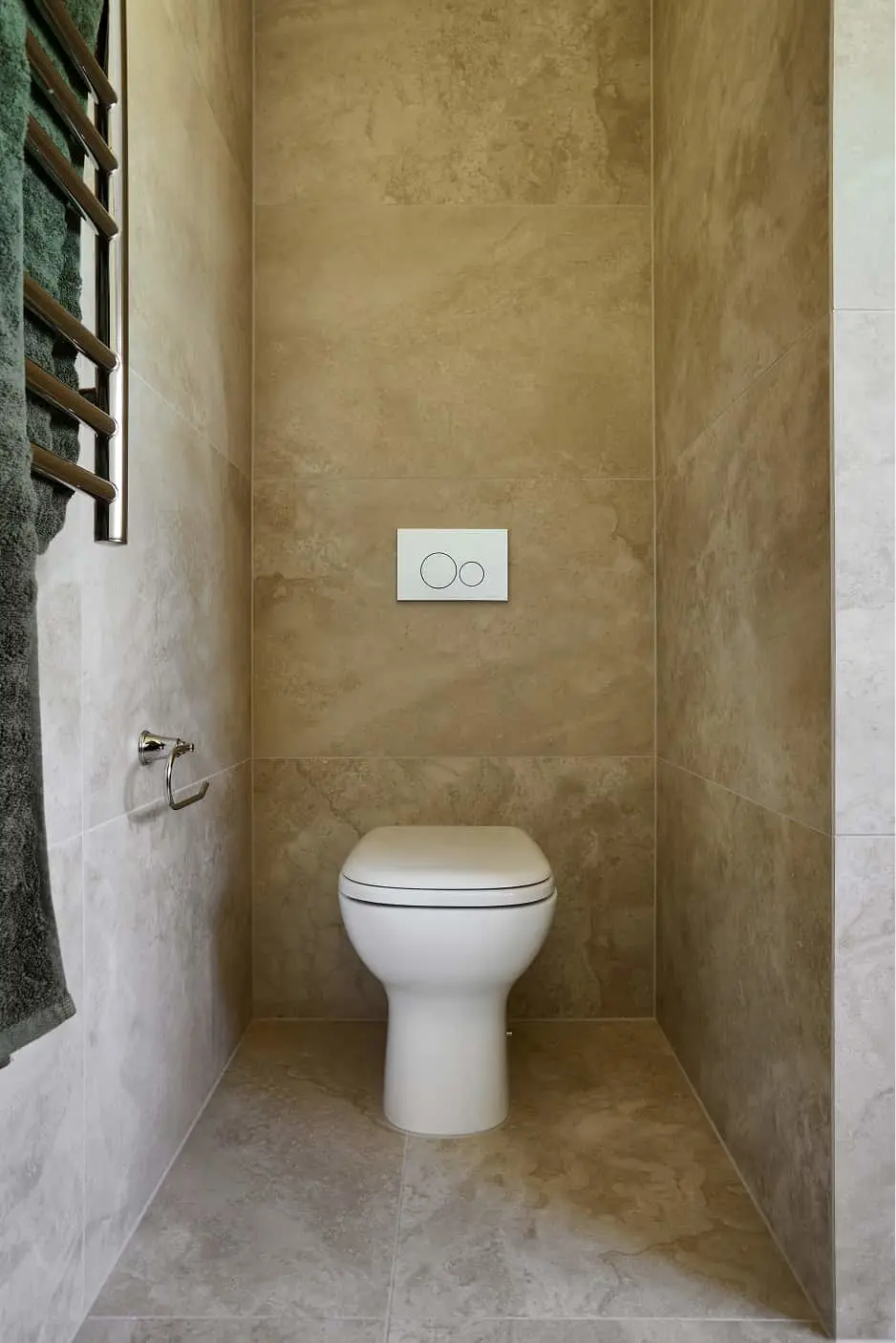 Modern bathroom with white wall-mounted toilet, beige stone tile walls, dual flush button, and towel rack.