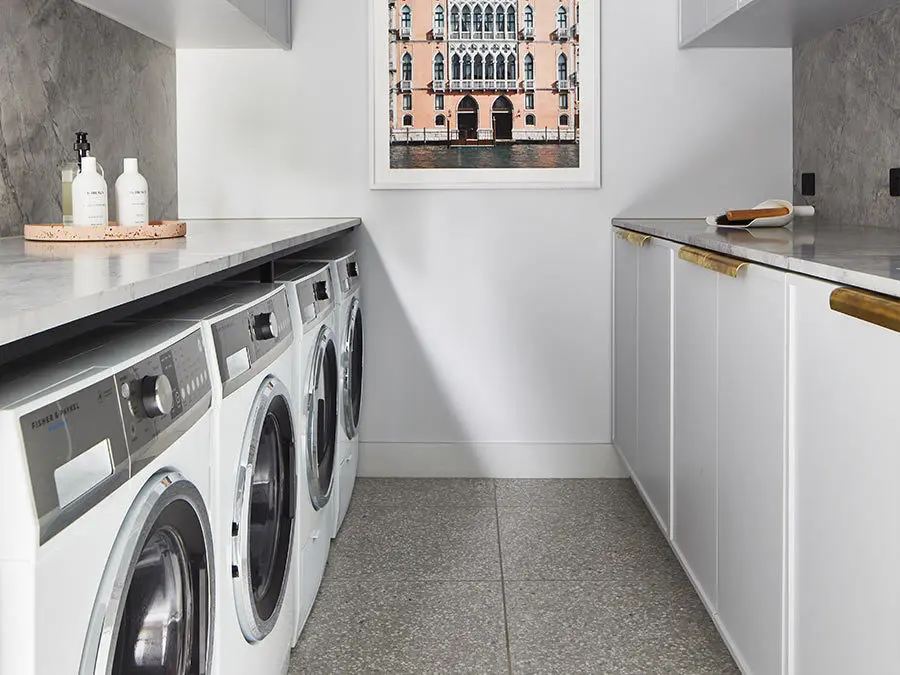 Modern laundry room with white appliances, marble countertops, and framed Venice canal artwork on the wall.