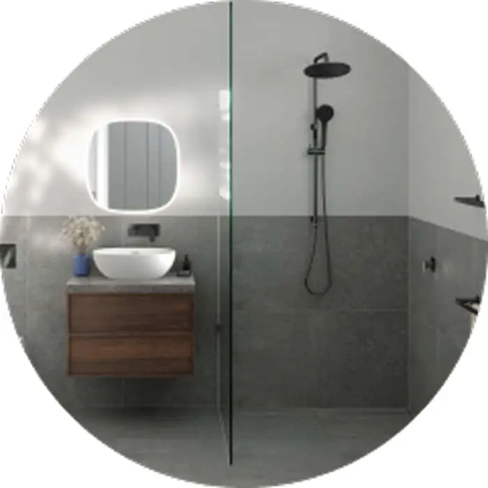 Modern bathroom with glass shower, wooden vanity with white basin, illuminated round mirror, and gray tiled walls.
