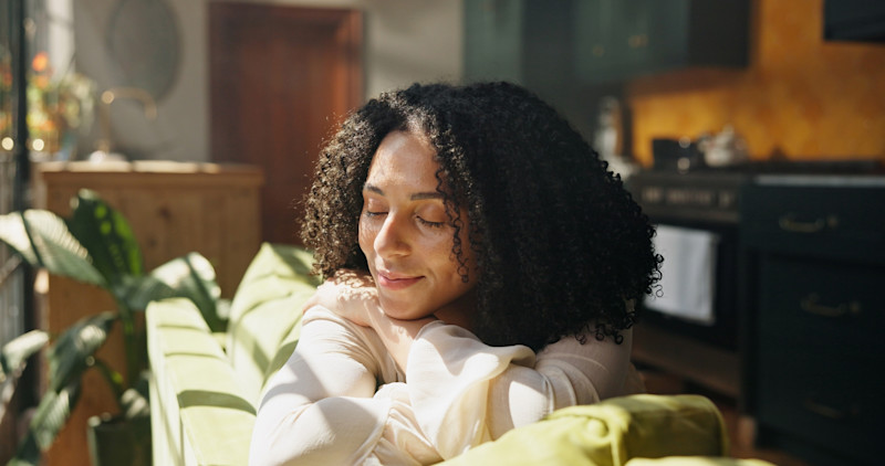 Black woman sitting on the couch with her eyes closed
