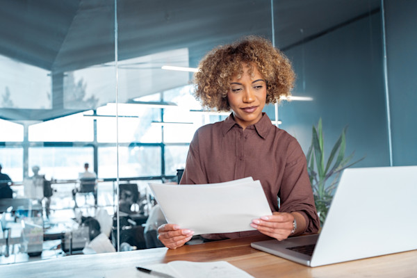 An African-American woman examines bills whiles working on her computer