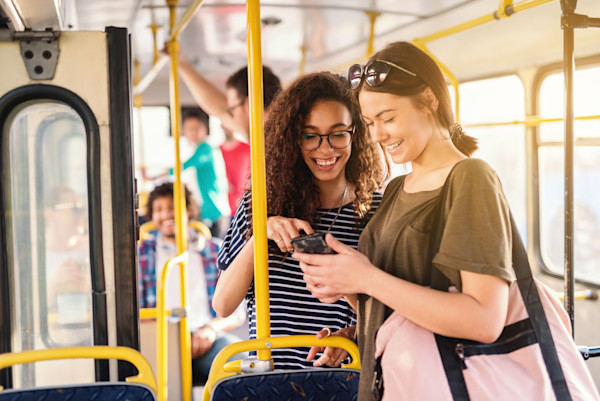 Two young women on a bus looking at a phone