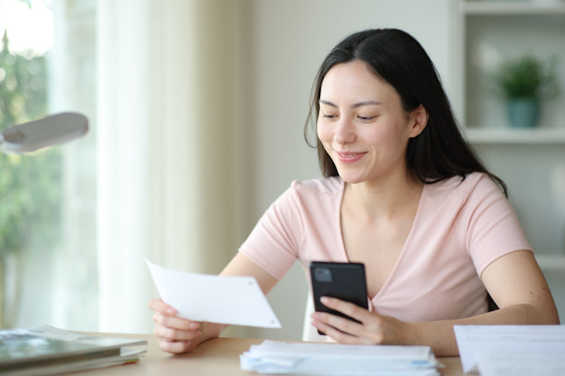 Asian woman happily reviews bills