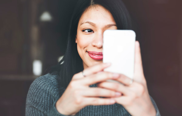 A woman smiling while viewing her phone