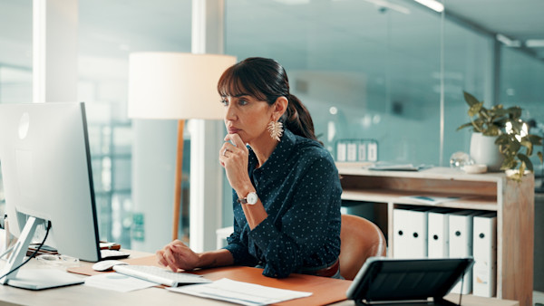 A middle-aged woman sits at a computer while she works