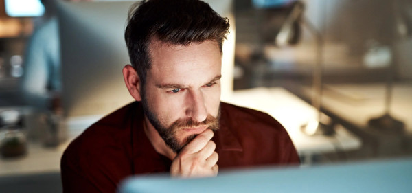 A man with a beard focused on his computer screen.