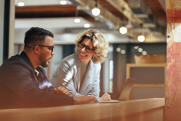 A smiling woman and man work in front of a computer