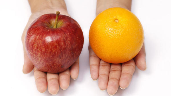 an apple and an orange sit in a person's palms