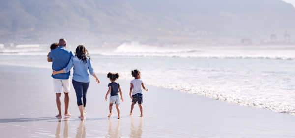 A black family of five walk along the beach