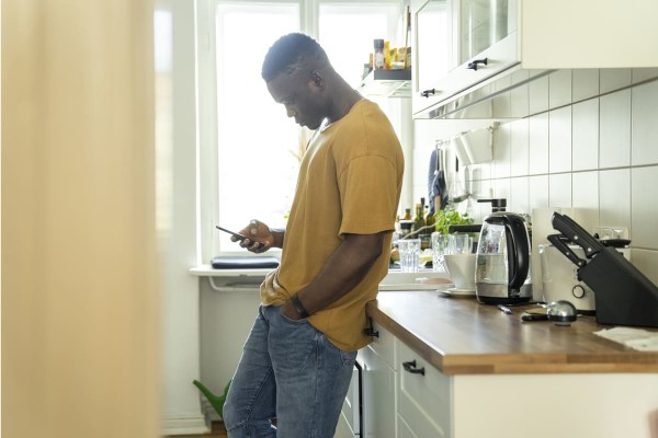 Man leaning against kitchen counter looking at his phone 