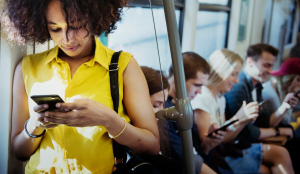 Woman with curly hair looking at her phone while standing in a bus
