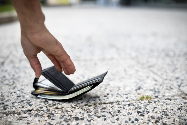 Close up of a hand picking up an open wallet on the floor