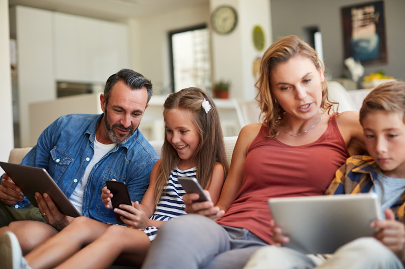 Family of four holding phones and tablets