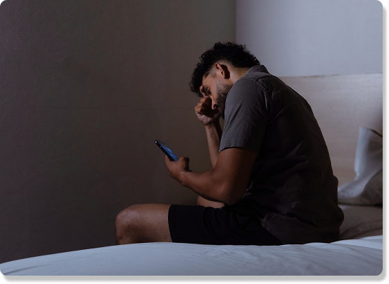 Person looking at a phone while sitting on a bed